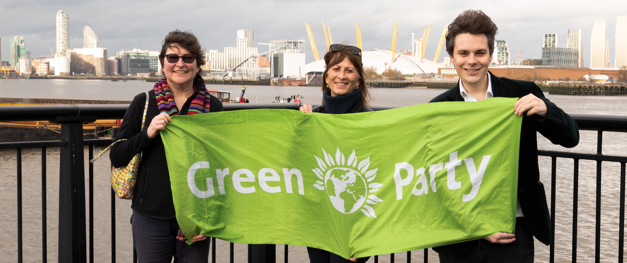 Stacy Smith, Karin Tearle and Matt Browne hold a Green Party banner in front of the River Thames