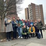 group of people standing outside with Orchard Estate flats in the background